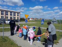 Policjantka i przedszkolaki w miasteczku ruchu drogowego przed szkołą