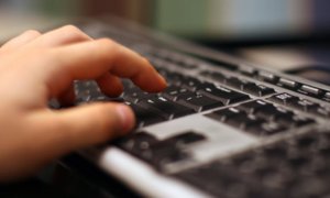 Dłoń pisząca na klawiaturze komputera.