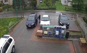 Zrzut ekranu z nagrania monitoringu. Parking przed sklepem. Z jednego z samochodów wysiada mężczyzna.