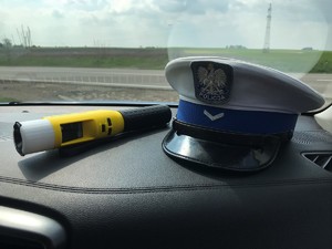Czapka policjanta wydziału ruchu drogowego i urządzenie do badania stanu trzeźwości na podszybiu radiowozu.