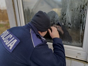 Policjant zagląda przez okno