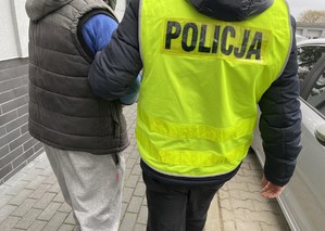 Policjant prowadzi zatrzymanego mężczyznę